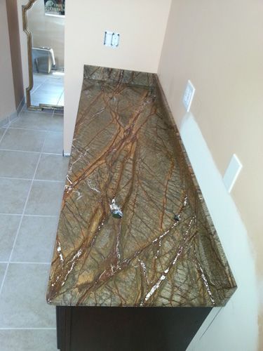 Brown and gold patterned countertop on a dark brown cabinet, installed against beige walls.