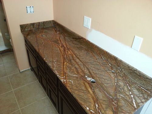 Brown granite countertop on dark cabinets, unfinished wall with electrical boxes.