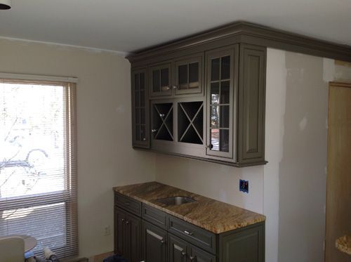 Dark green cabinets with a granite countertop in a kitchen; near a window.