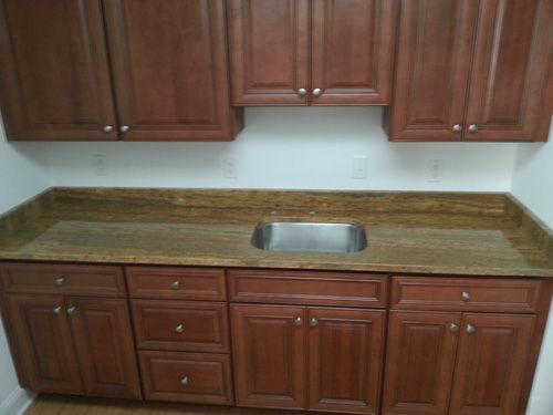 Brown kitchen cabinets with a granite countertop and a stainless steel sink.