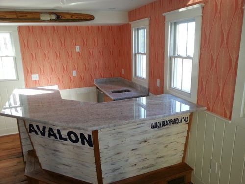 Bar with granite countertop, peach wave wallpaper, Avalon on the side, and two windows.