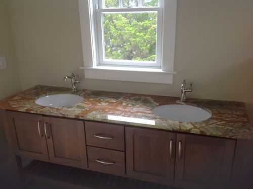 Bathroom with double sinks, wooden vanity, granite countertop, and a window.