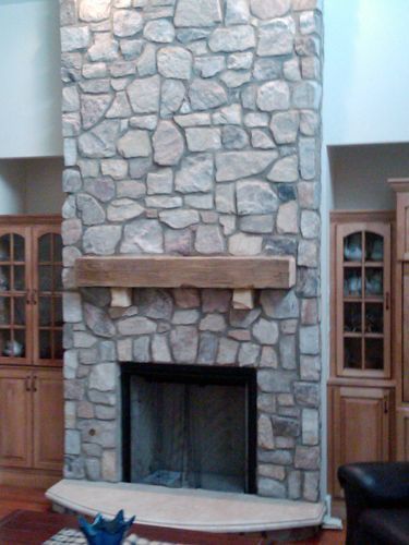 Stone fireplace with wooden mantle and built-in cabinets on either side.