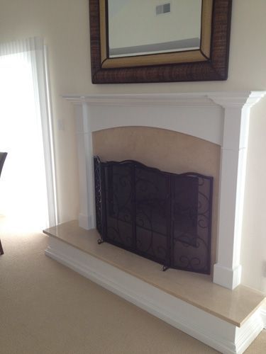 Fireplace with white mantle, beige hearth, black screen, and mirror above.