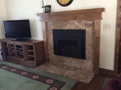 Fireplace with stone surround and wooden mantel; TV on matching cabinet.