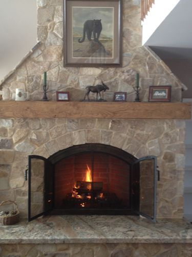 Stone fireplace with burning fire, wooden mantel holding decor, and a framed painting.