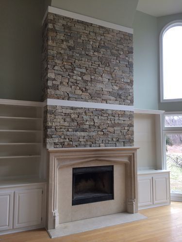 Stone fireplace with built-in bookshelves and tall, arched window. The walls are pale green.