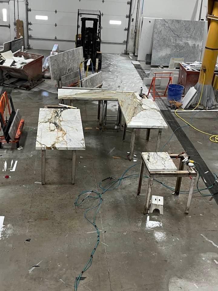 Granite countertops being worked on in a workshop, with tools and a forklift.