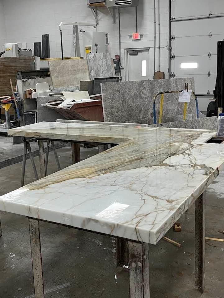 A marble countertop with gold veining, being worked on in a workshop setting.