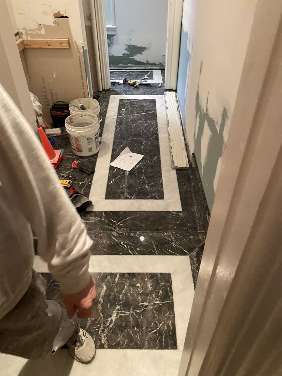 Hallway with dark marble tile, white border, and person in the foreground.