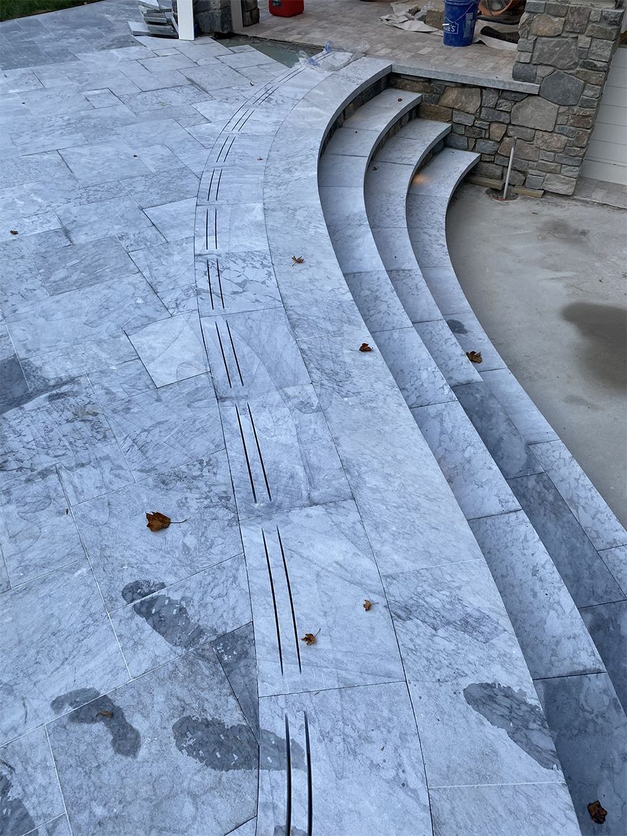 Curved outdoor stone steps and walkway. Gray stone with cut lines for drainage.