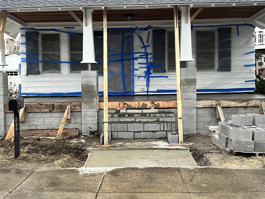 House porch under construction, concrete steps, cinder block pillars, wrapped windows.