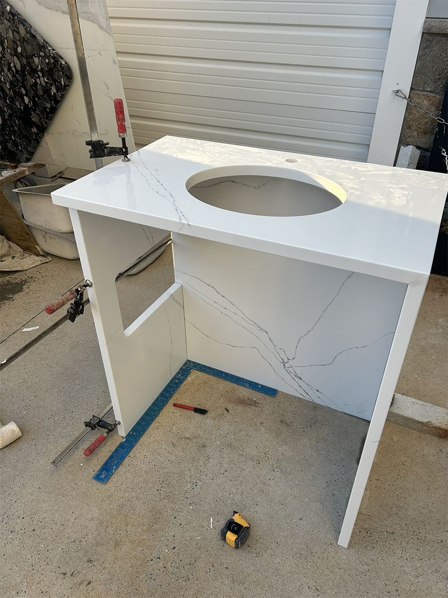 White quartz countertop vanity with sink cutout, under construction outside.