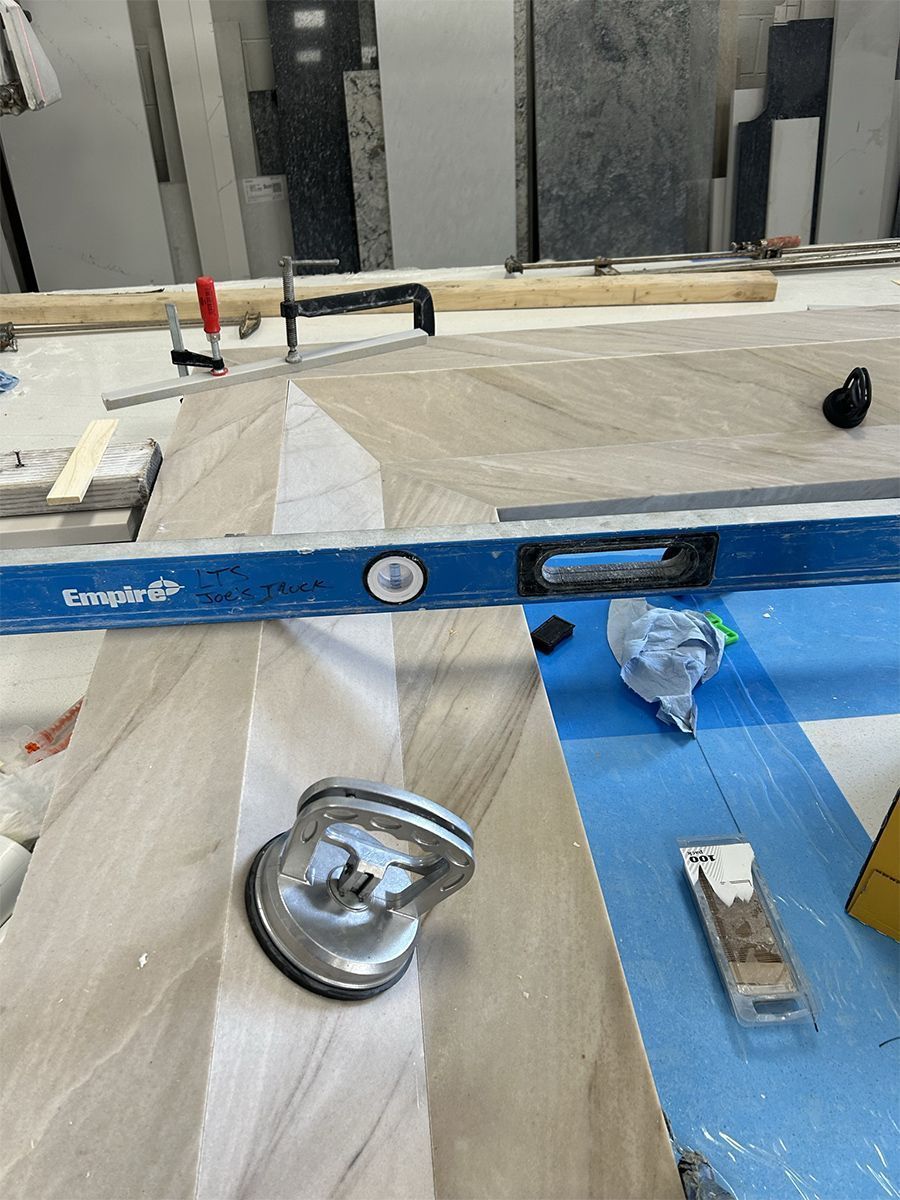 A level and suction cup on a light and dark stone surface during construction.