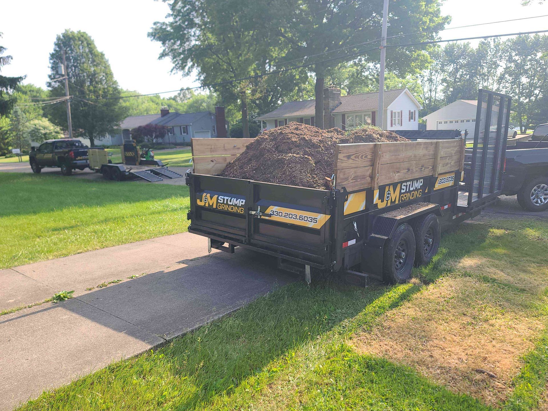 A trailer with a load of dirt on it is parked on the side of the road.
