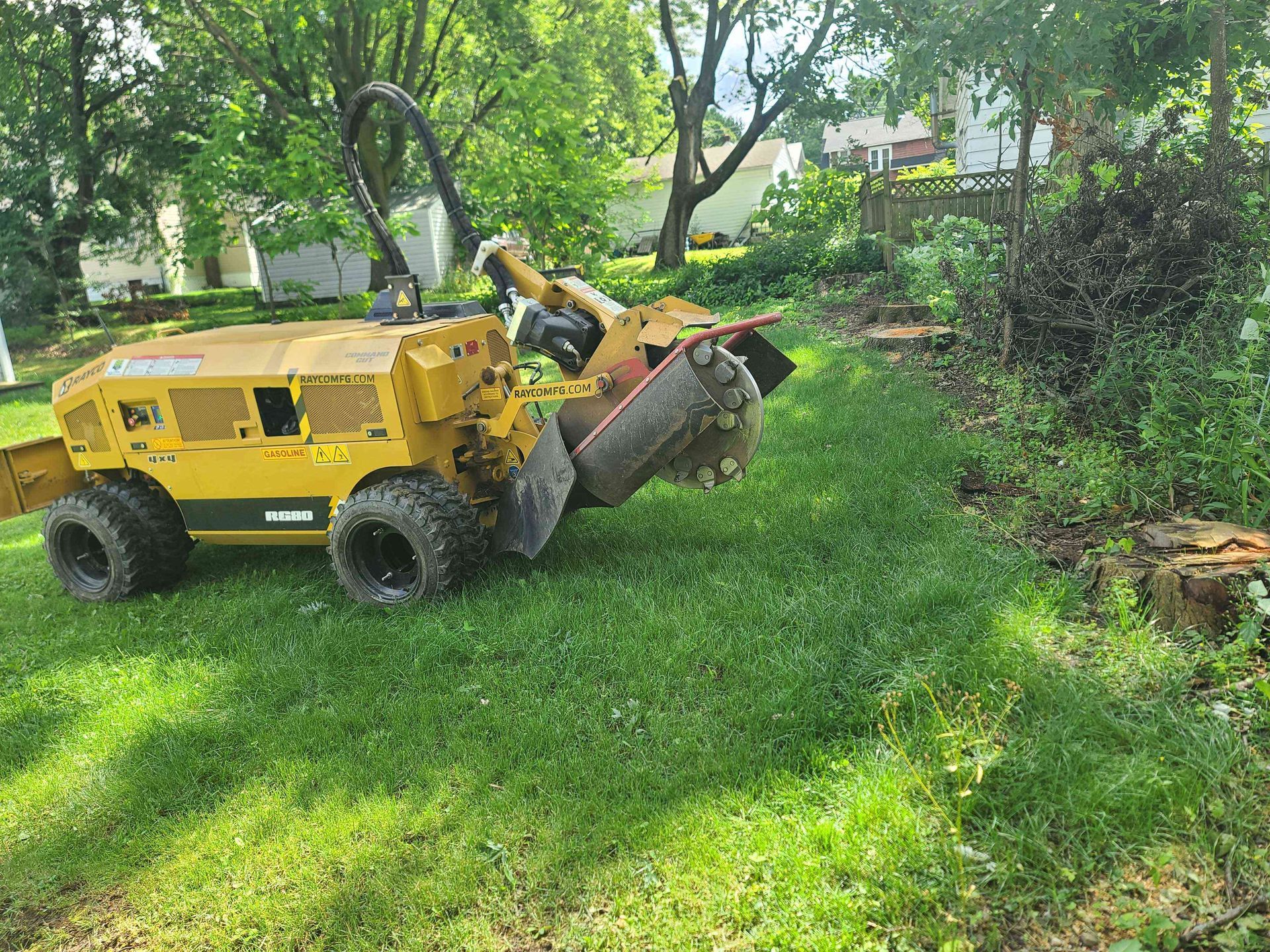 A stump grinder is sitting in the grass next to a tree stump.