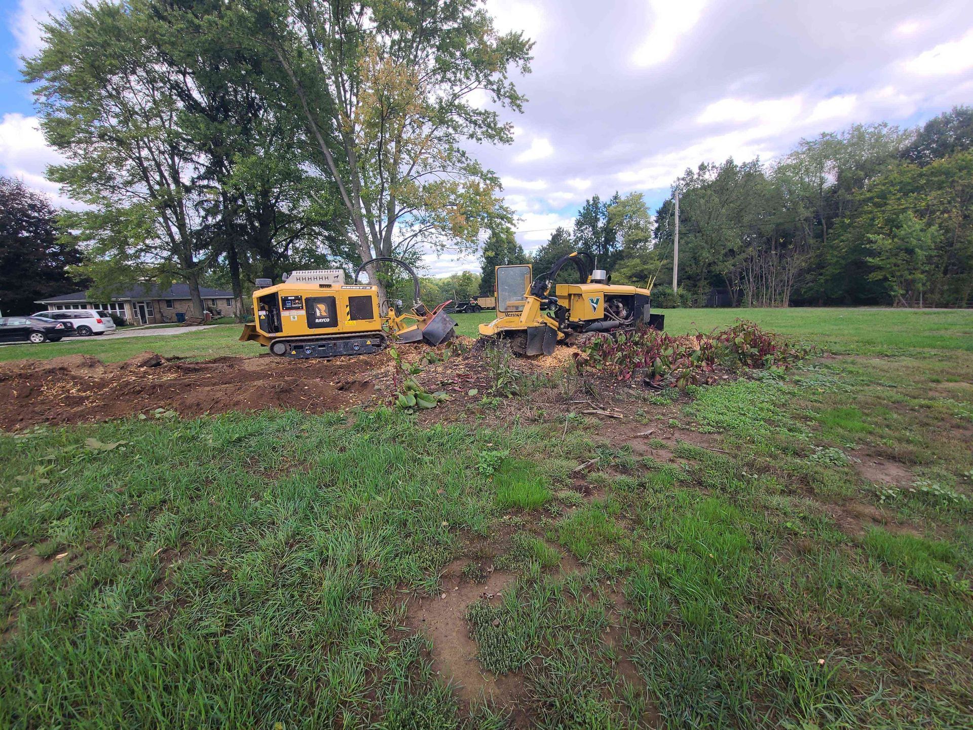 Two bulldozers are working in a grassy field.