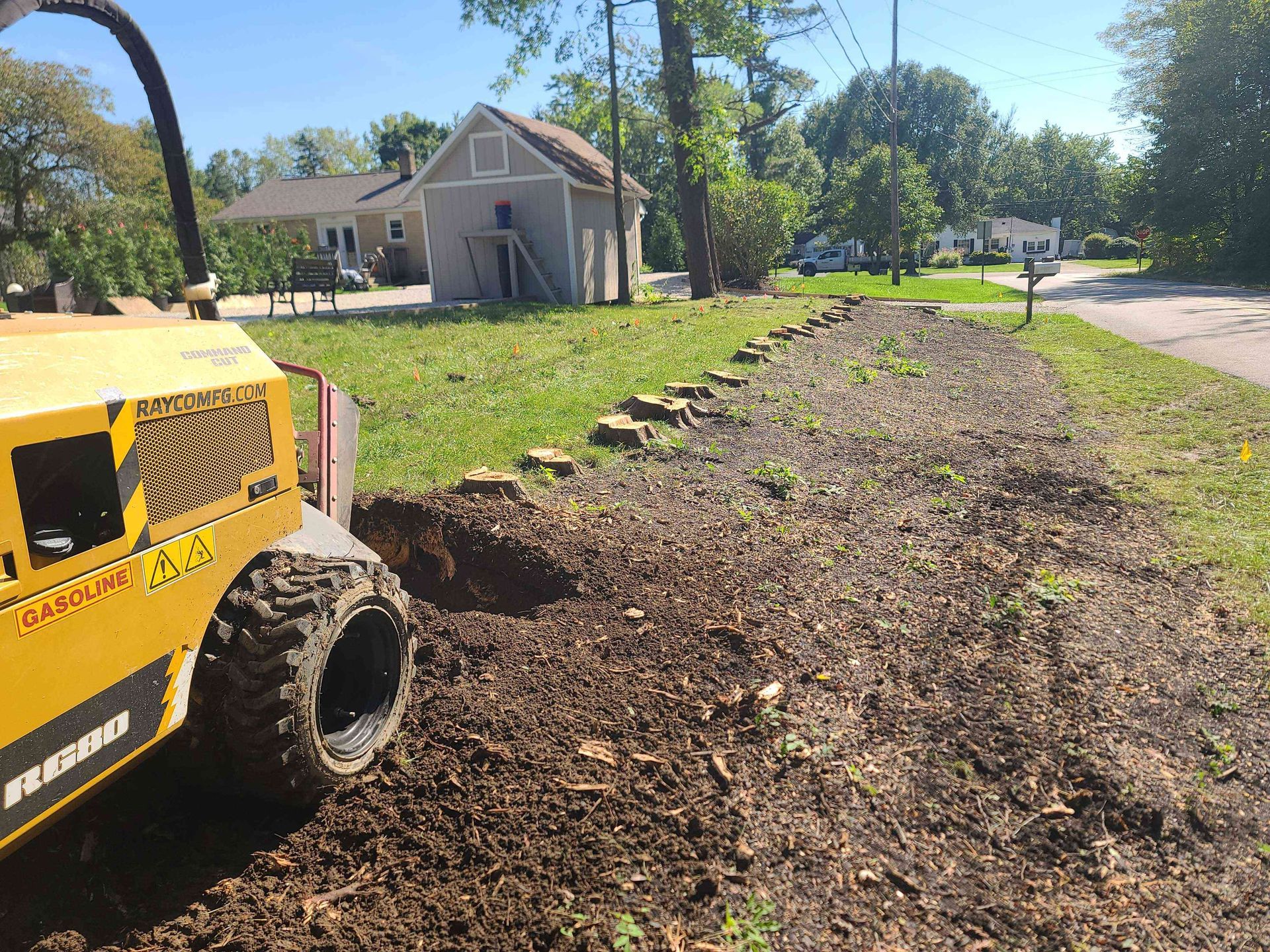A yellow tractor is sitting in the dirt in front of a house.