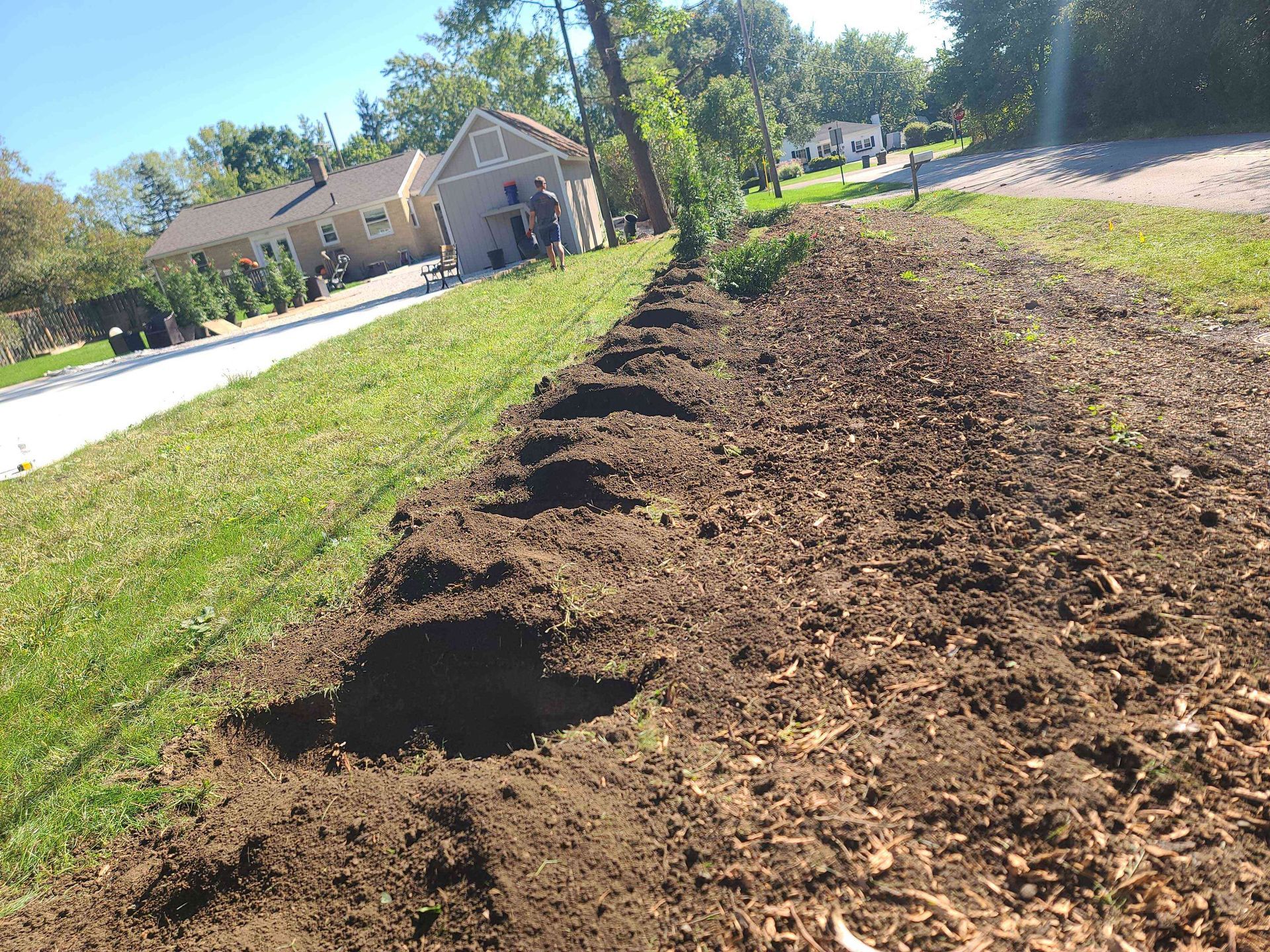 A pile of dirt is sitting on the side of a road next to a house.