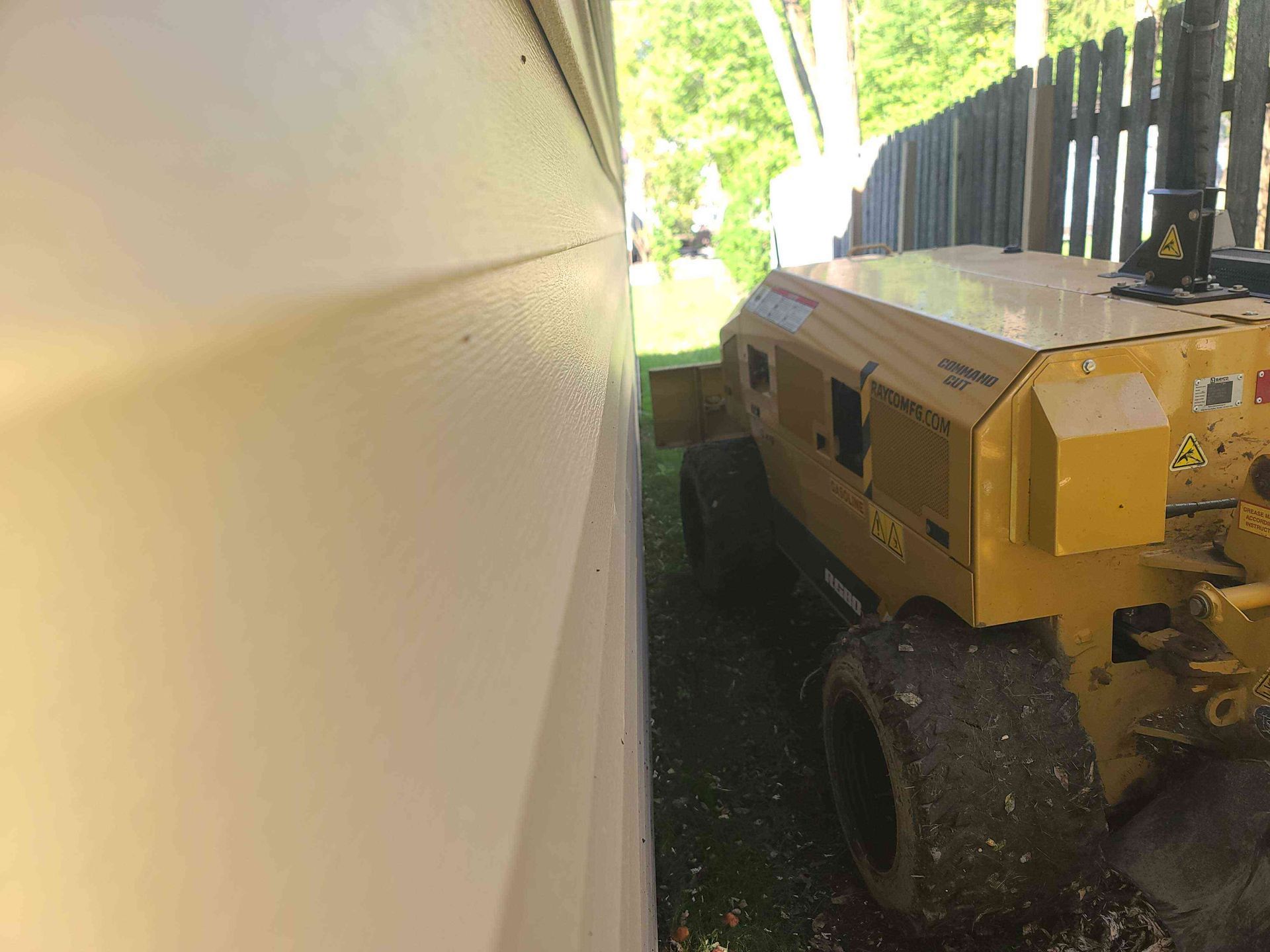 A large yellow machine is parked next to a white wall.