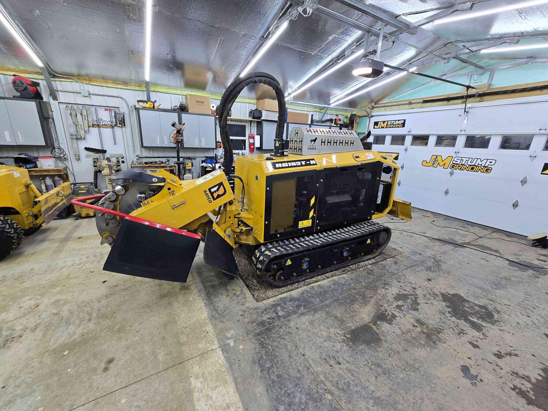 A yellow tractor is parked in a garage next to a garage door.
