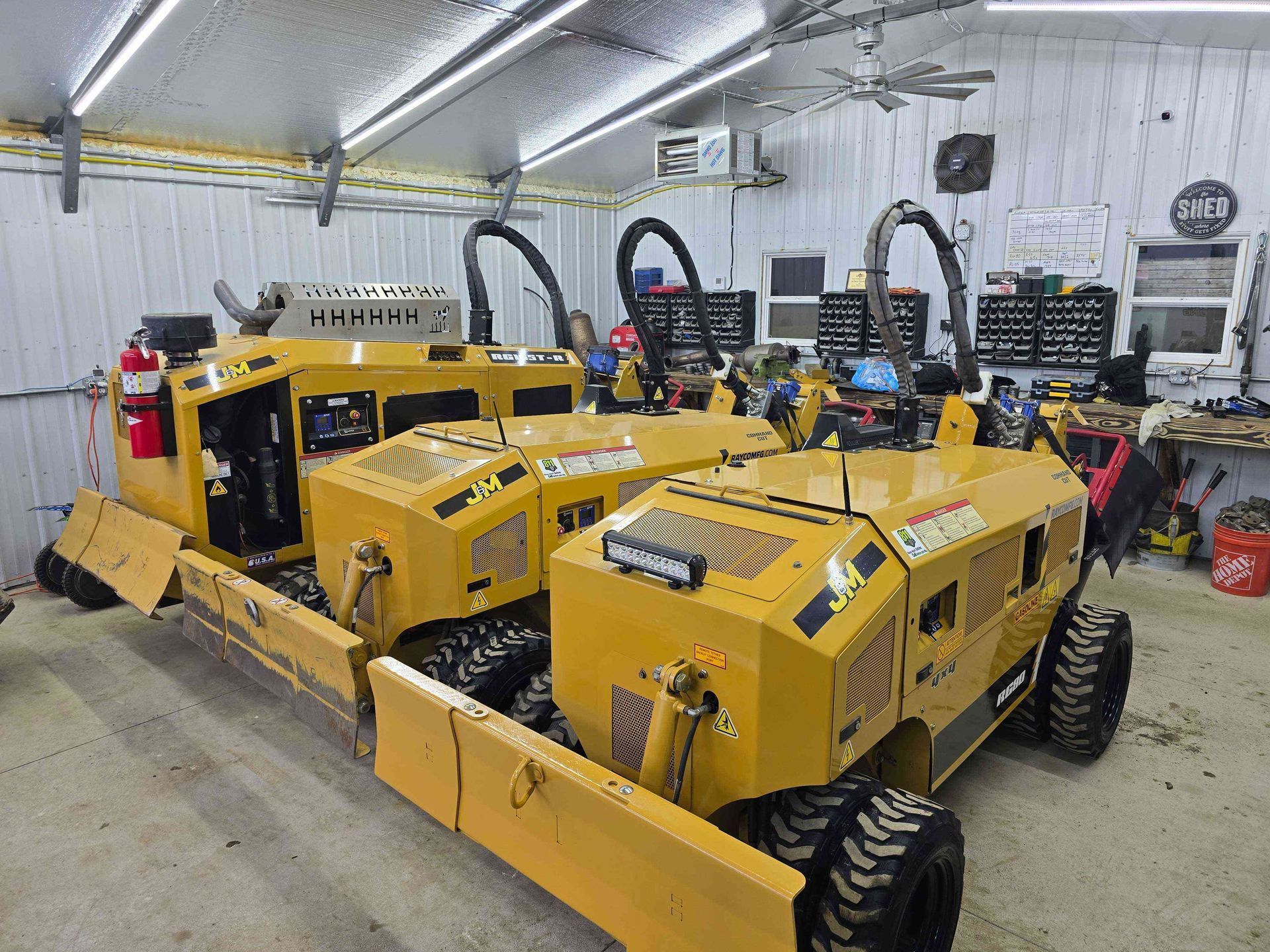 Three yellow tractors are parked in a garage.