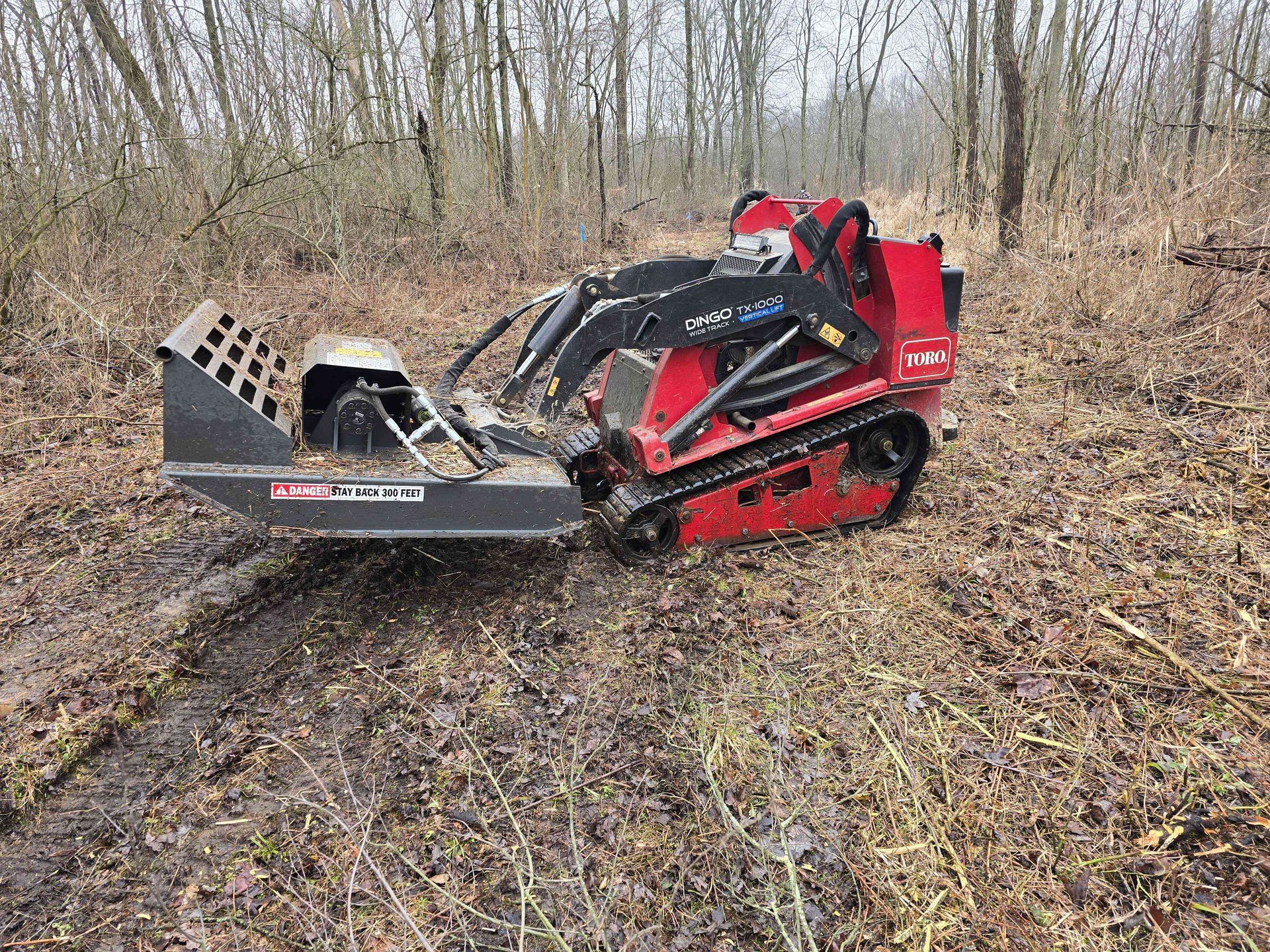 A red and black machine is sitting in the middle of a forest.