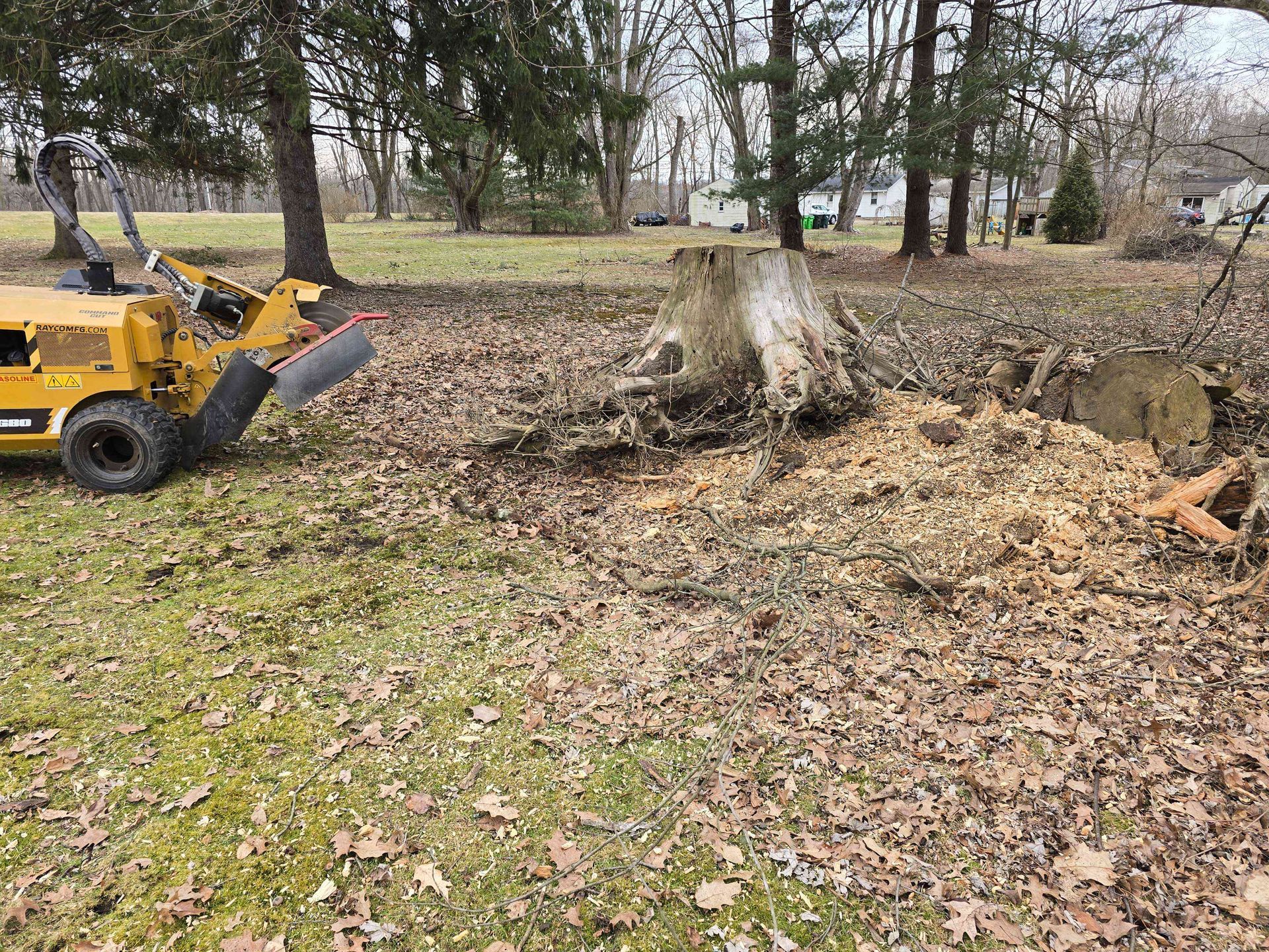 A tree stump is being removed by a machine in a yard.