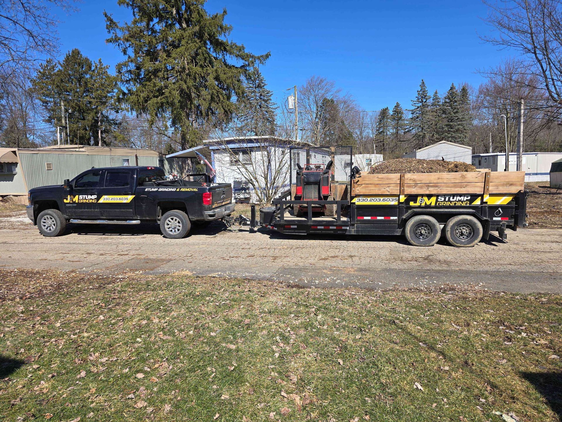 Two trucks are parked next to each other on a dirt road.