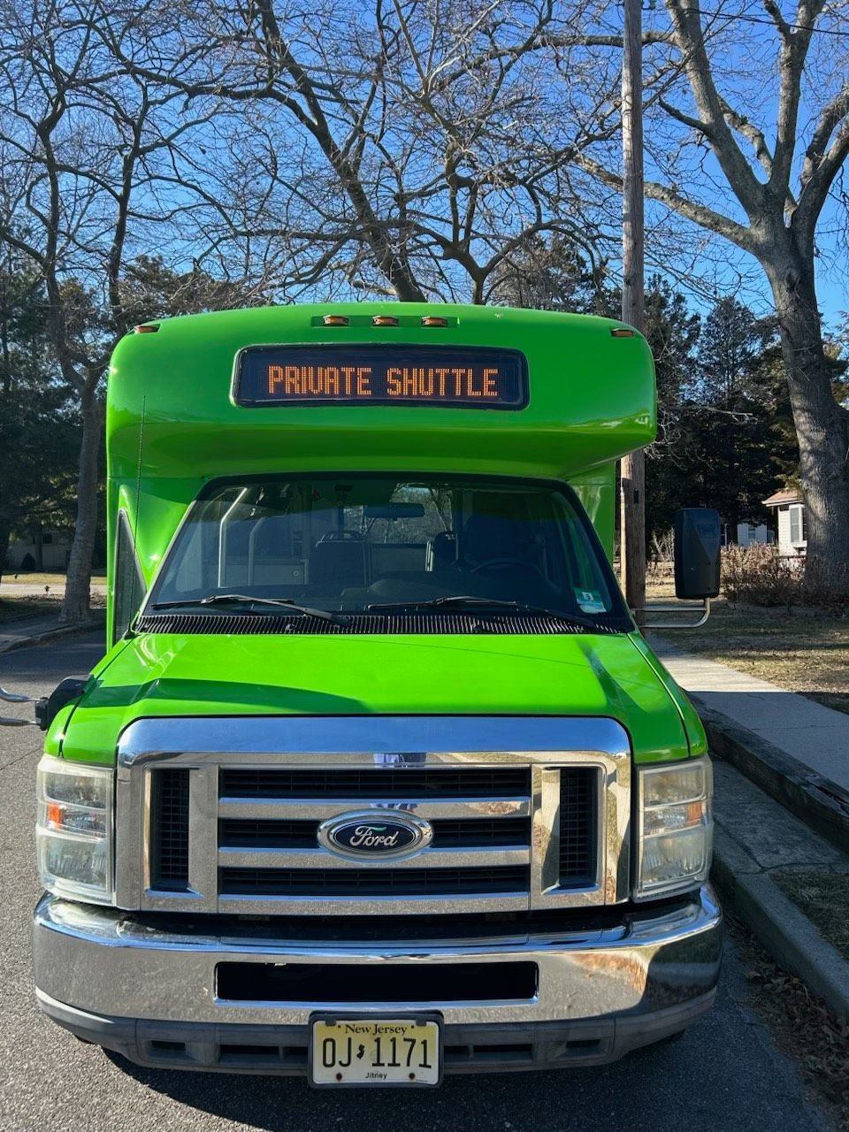 A green shuttle bus is parked on the side of the road.