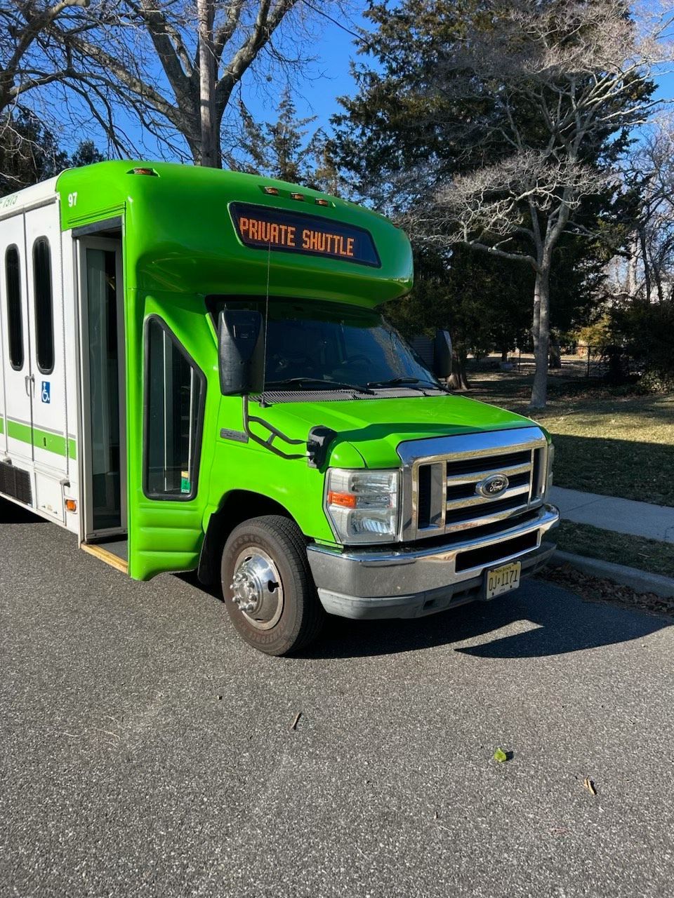 A green and white bus is parked on the side of the road.