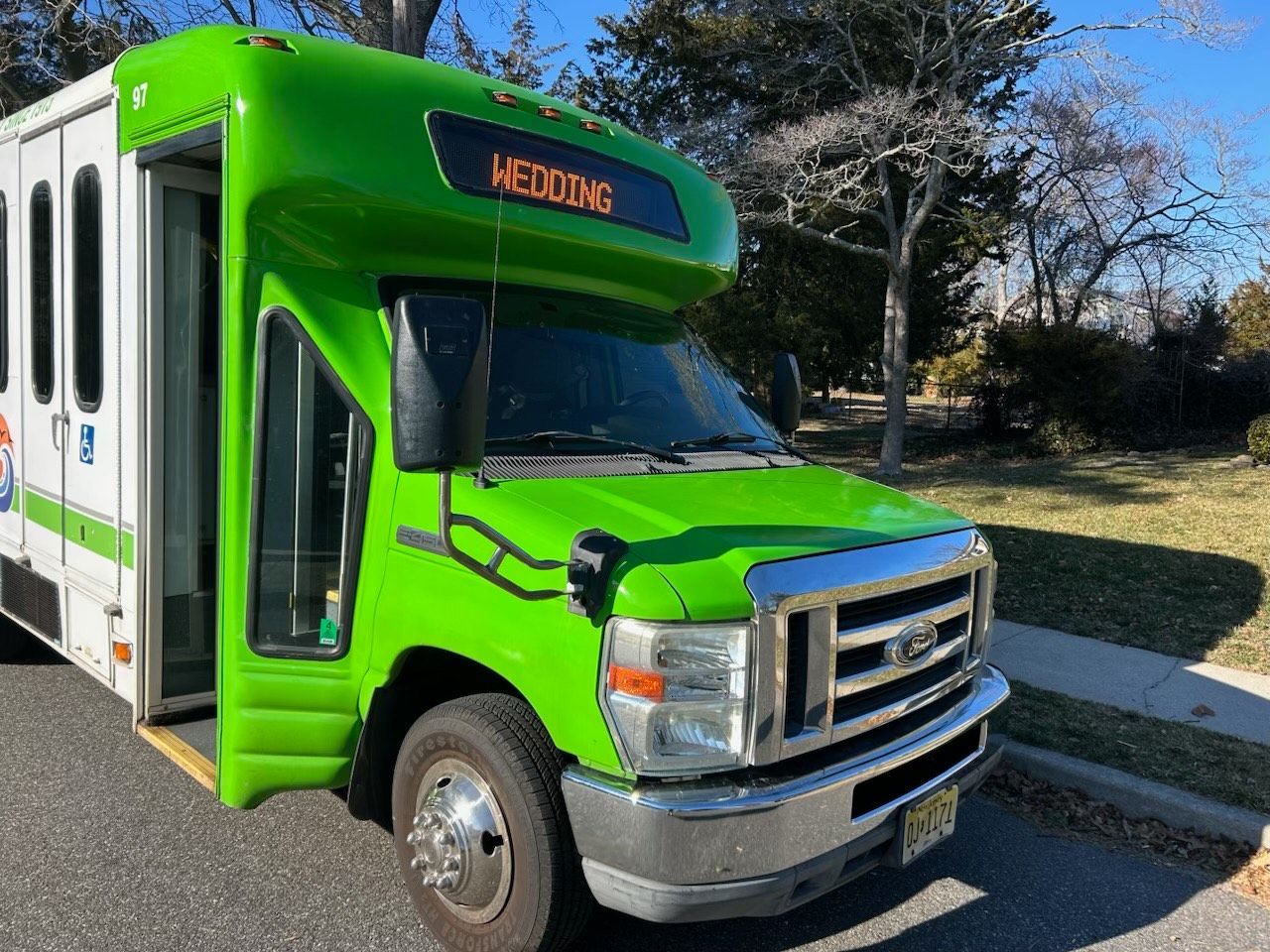 A green shuttle bus is parked on the side of the road.