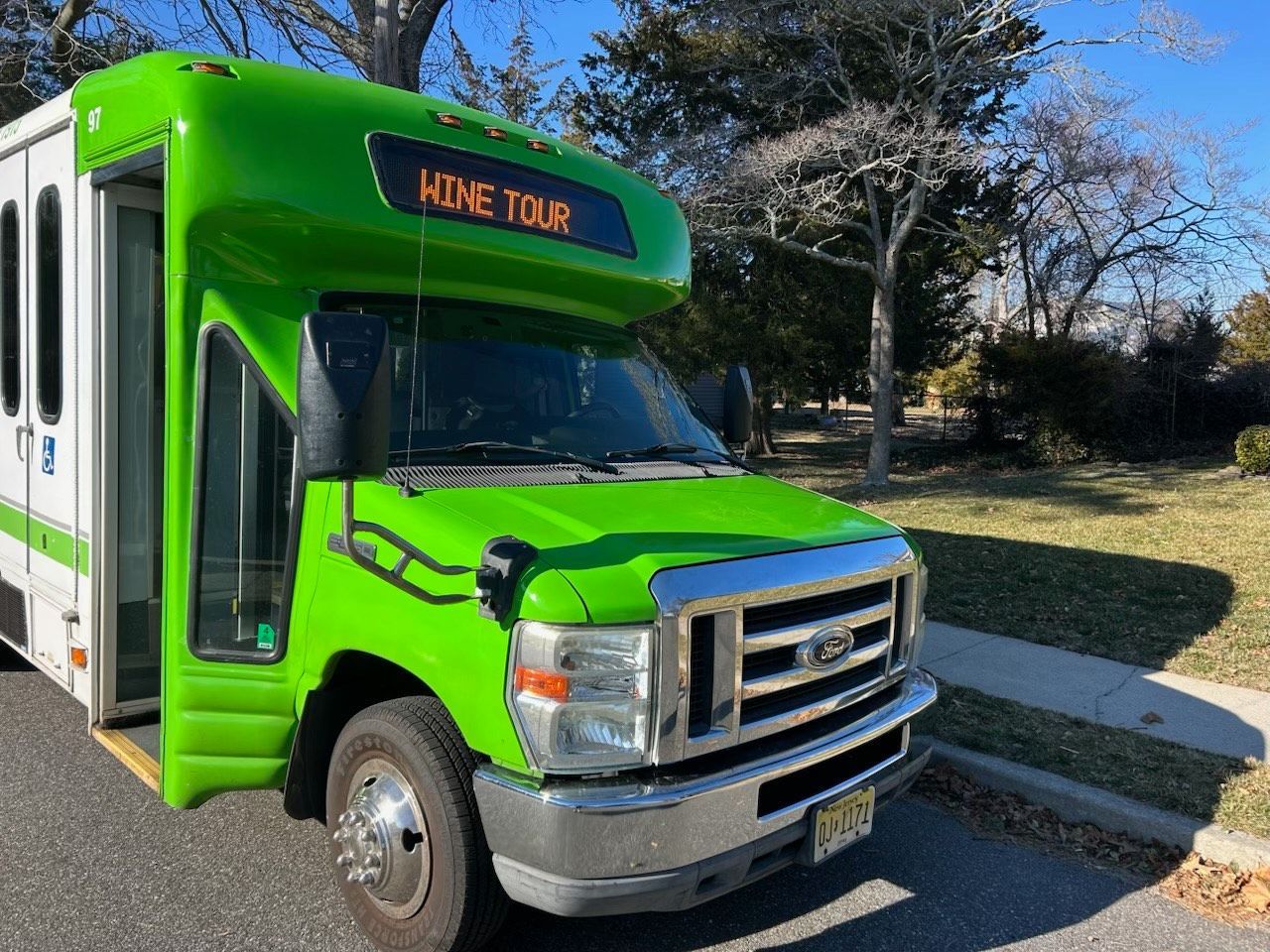 A green bus is parked on the side of the road.