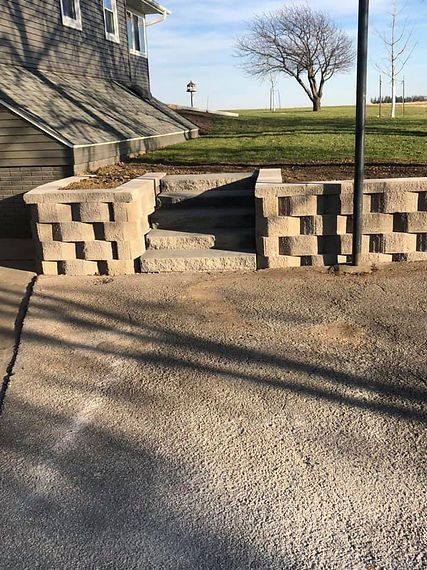 Stone steps leading up to a building, flanked by block walls. Sunny day.