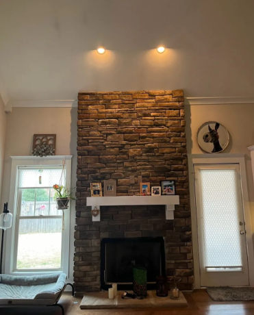 Living room fireplace with stone surround, white mantel, and two wall lights above.