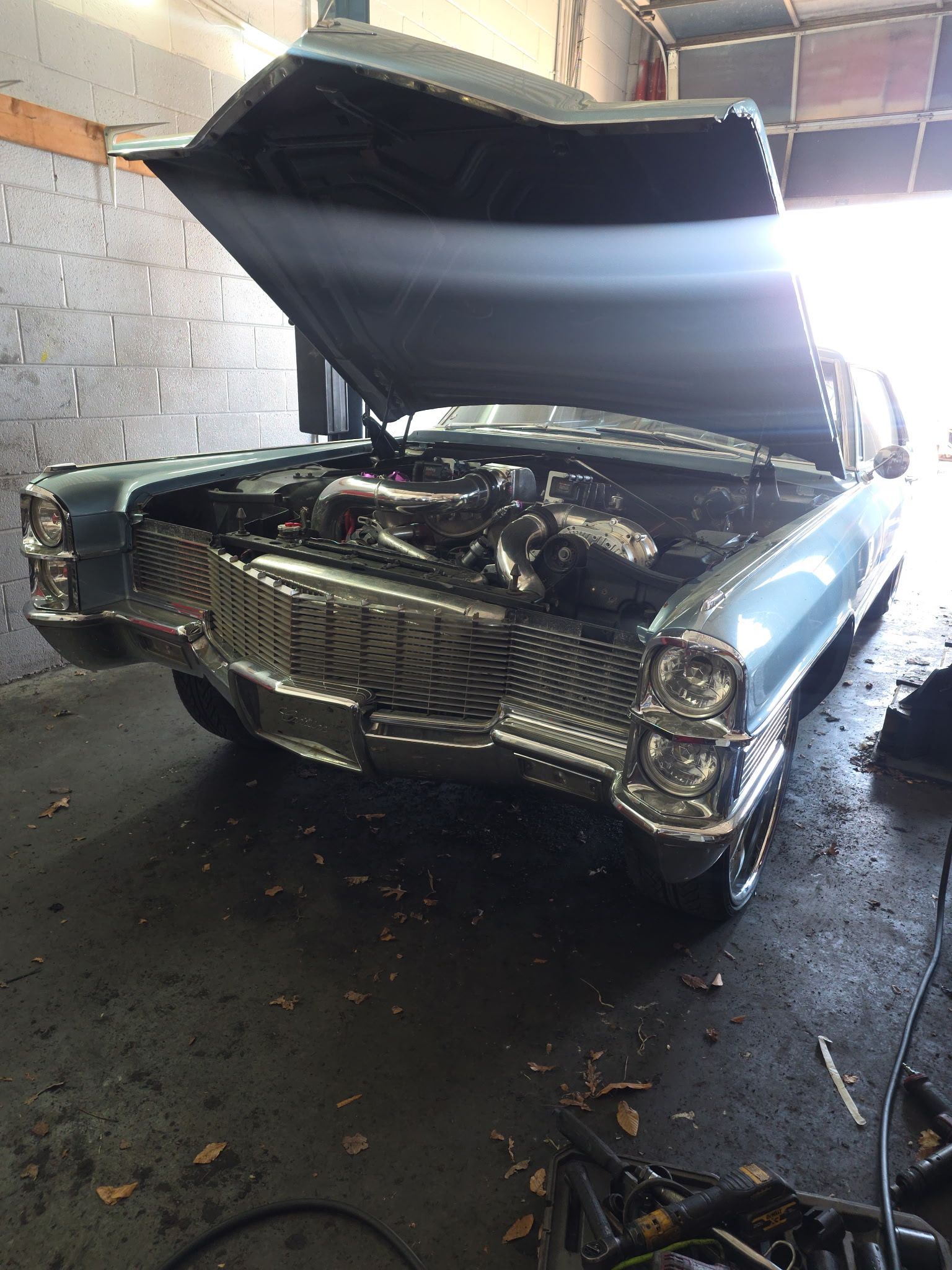 Classic car in a garage with hood open, showing the engine and front grille.