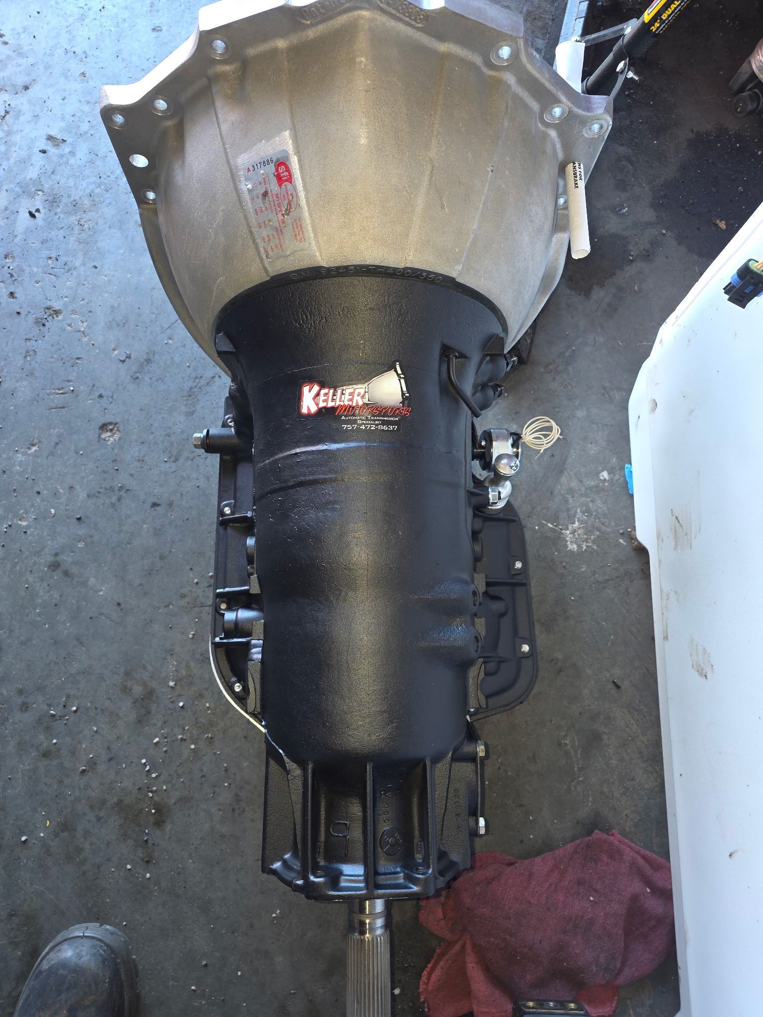 Black cylindrical mechanical assembly with a silver top, lying on a concrete floor