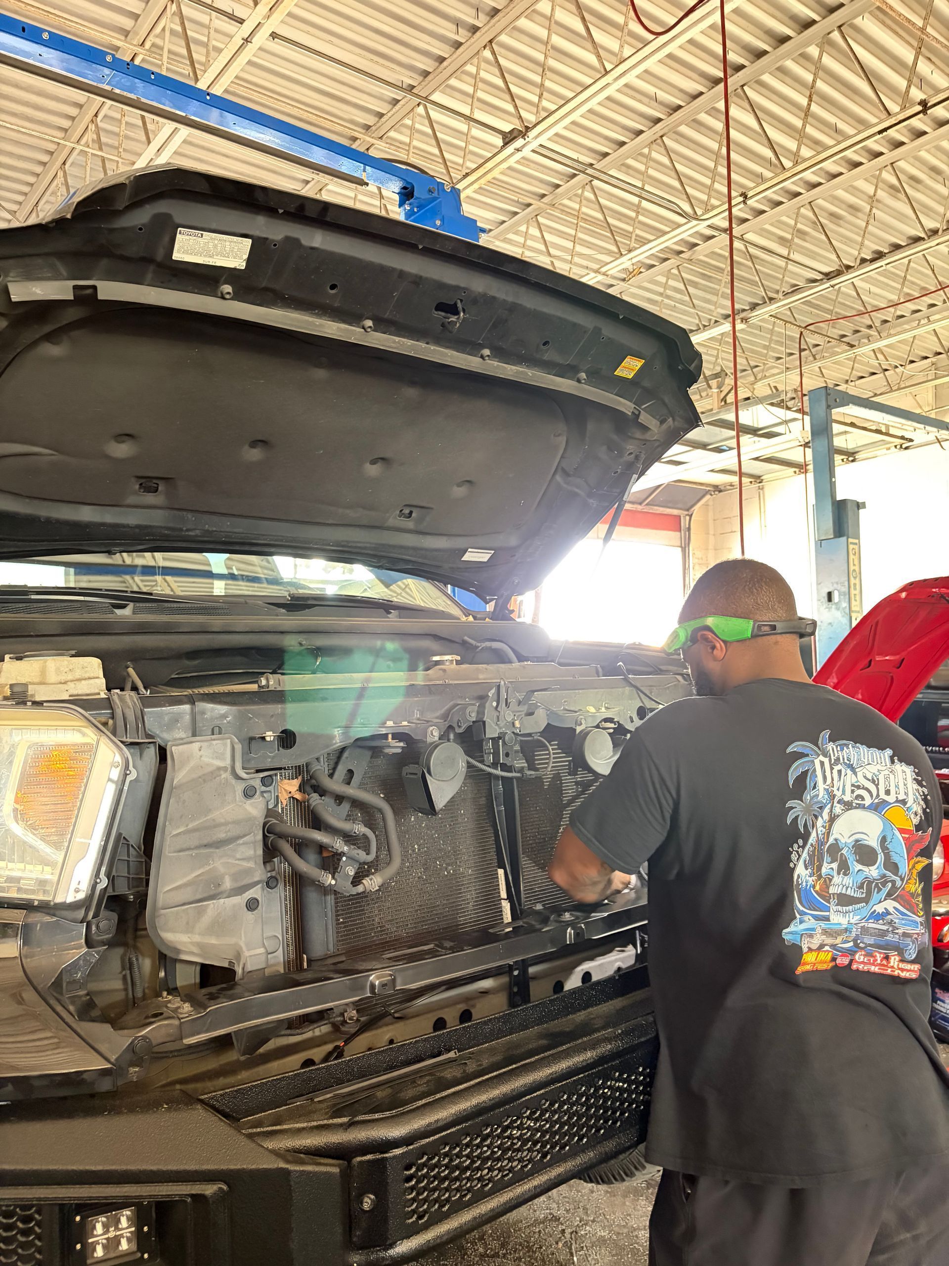 Mechanic working on a truck with the hood open inside a garage