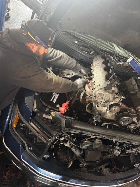 Close-up of a rusty metal exhaust manifold header attached to a bright red engine block with visible mounting bolts.