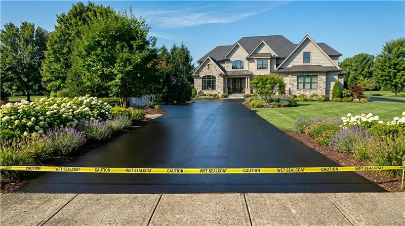 Person standing on asphalt paving machine, laying asphalt on a surface.