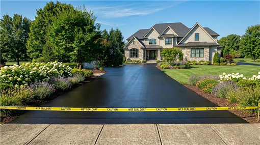 Person standing on asphalt paving machine, laying asphalt on a surface.