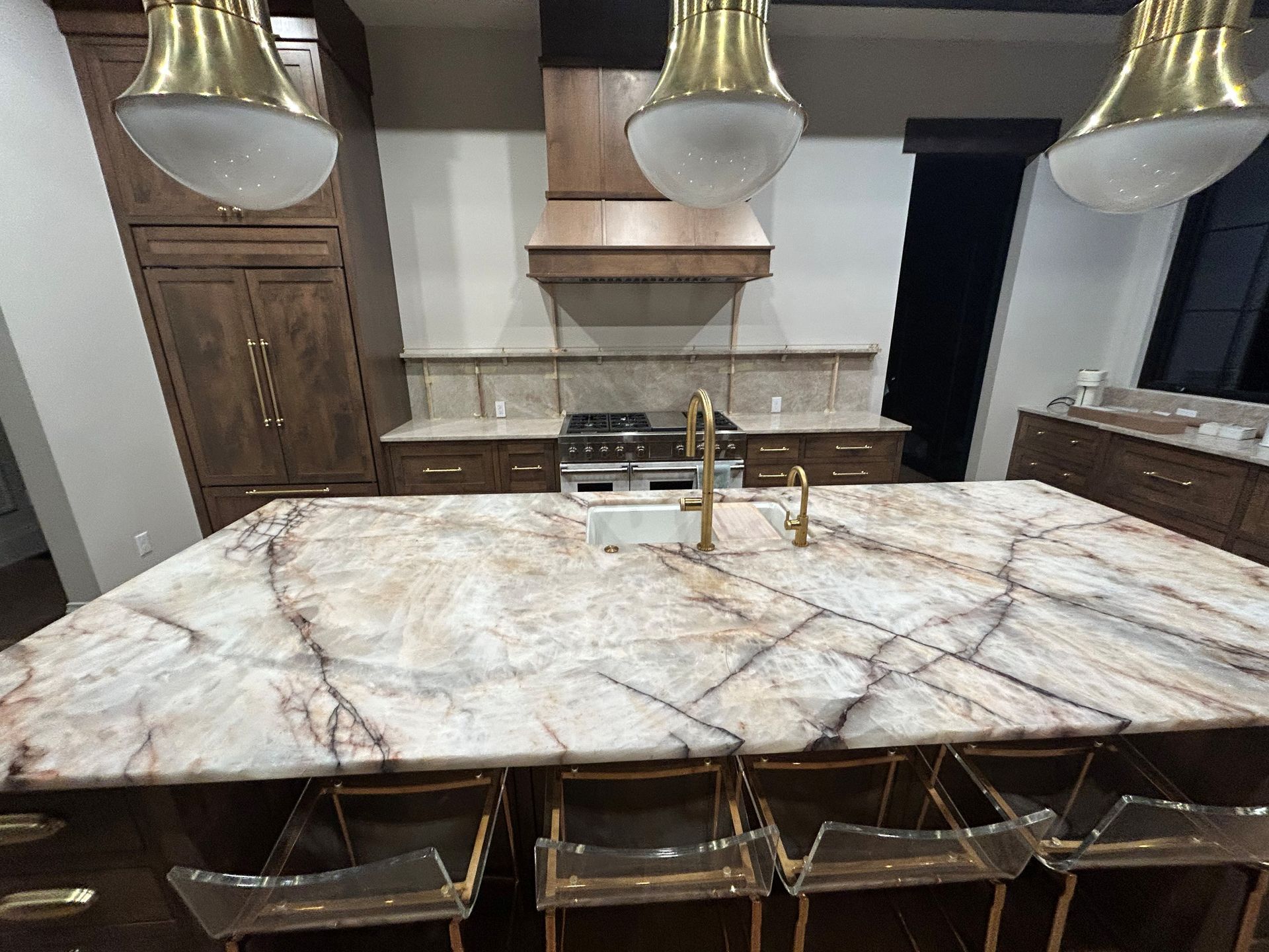 A kitchen with a large island with a patterned countertop and gold accents.