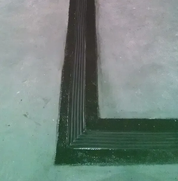 Black painted angular trim on a light green floor.
