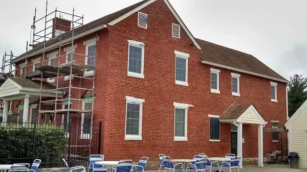 Red brick building with white window frames and scaffolding.