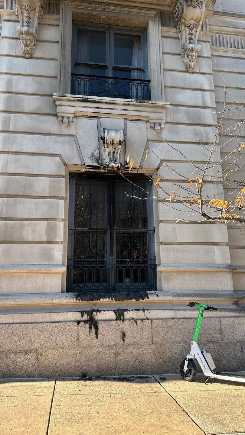 Exterior of building with damaged window, black soot, and a parked lime scooter.