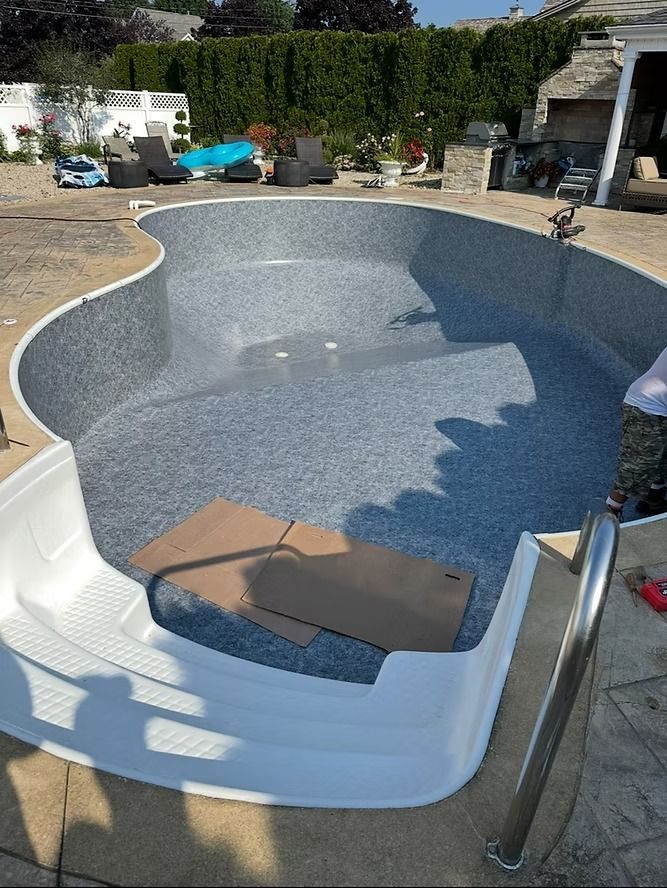 Pool with new blue speckled liner, white steps, and a metal ladder. Cardboard sits in the shallow end.