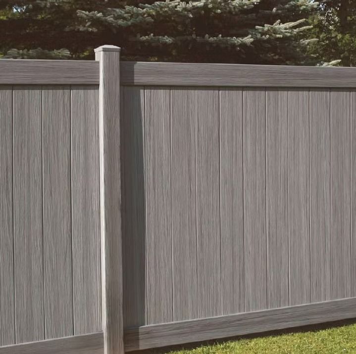 Gray vertical wood-look fence with matching post, outdoors.