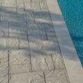 Stone patio edge next to a pool with clear blue water.