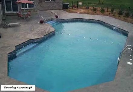 An angular, light-blue backyard swimming pool with a stone patio, steps, and a rope line, viewed from an elevated angle.