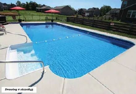 An outdoor rectangular swimming pool with blue water and white steps, surrounded by a light-colored patio and a fence.